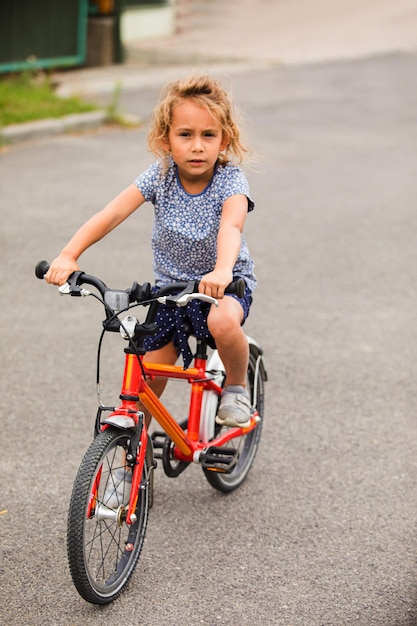 La petite fille fait du vélo dans la ville