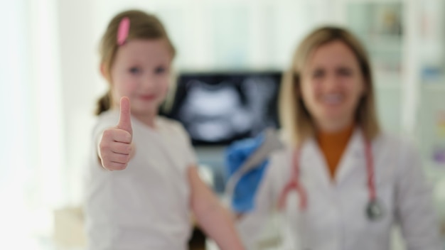 Une petite fille fait un geste de pouce en l'air lors d'un rendez-vous chez le médecin