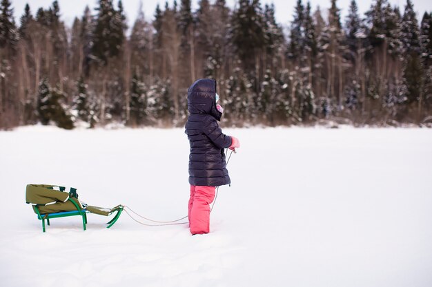 Petite fille fait de la luge par une chaude journée d'hiver