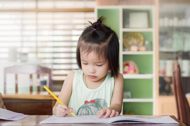 Une petite fille fait ses devoirs sur le bureau