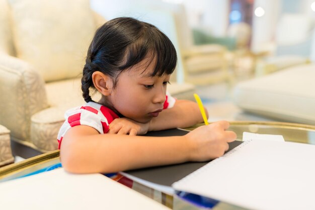 La petite fille fait ses devoirs, écrit sur un livre.