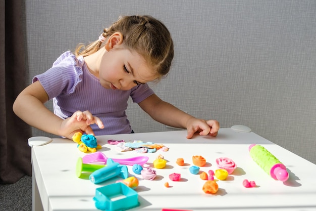 Petite fille a fait de la tortue en pâte à modeler sur une table blanche à la maison la motricité des enfants développant des jeux fond de pâte à modeler