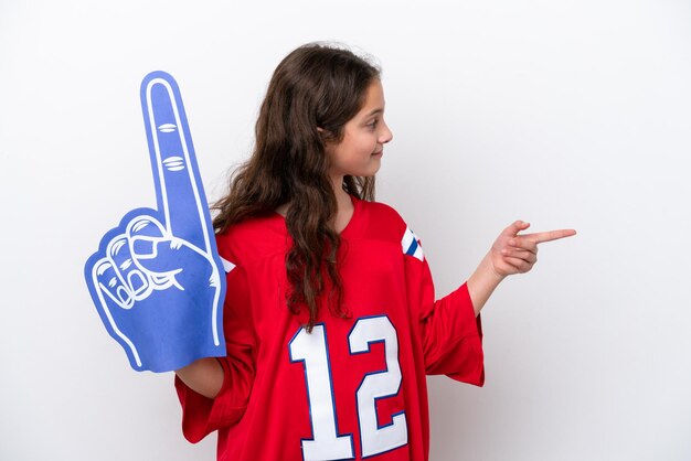 Photo petite fille fan de sport isolée sur fond blanc pointant vers le côté pour présenter un produit