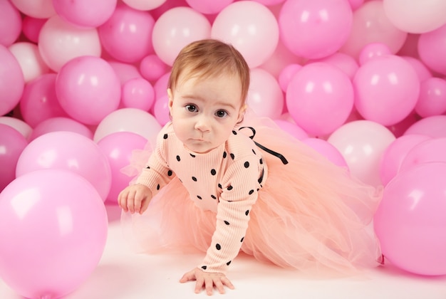 Petite fille fête son premier anniversaire. Fille sur fond de ballons roses. Vue de dessus