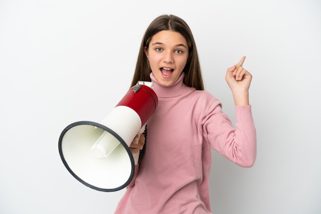 Petite fille sur fond blanc isolé criant à travers un mégaphone et pointant du côté