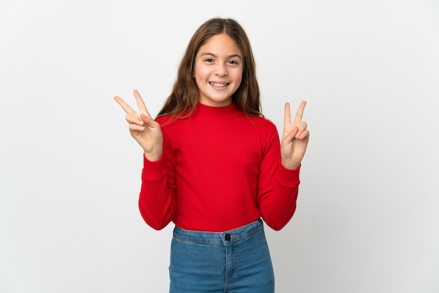 Petite fille sur fond blanc isolé montrant le signe de la victoire avec les deux mains