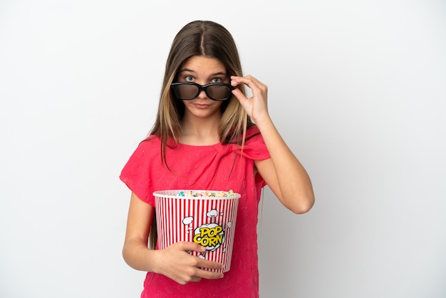 Petite fille sur fond blanc isolé surpris avec des lunettes 3d et tenant un grand seau de pop-corn