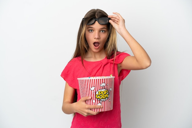 Petite fille sur fond blanc isolé surpris avec des lunettes 3d et tenant un grand seau de pop-corn