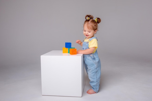 petite fille sur fond blanc et jouant avec des cubes colorés. jouet pour enfant cu