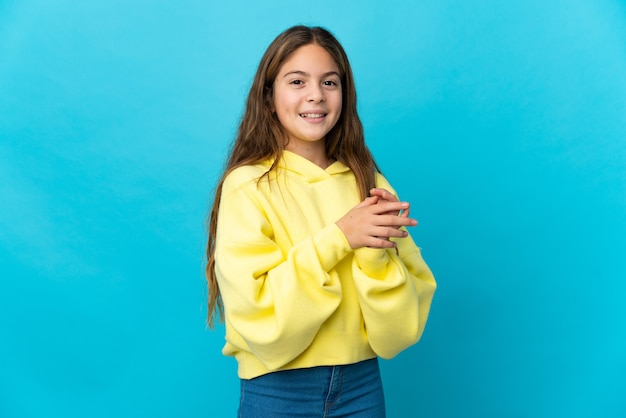 Petite fille sur fond bleu isolé applaudissant