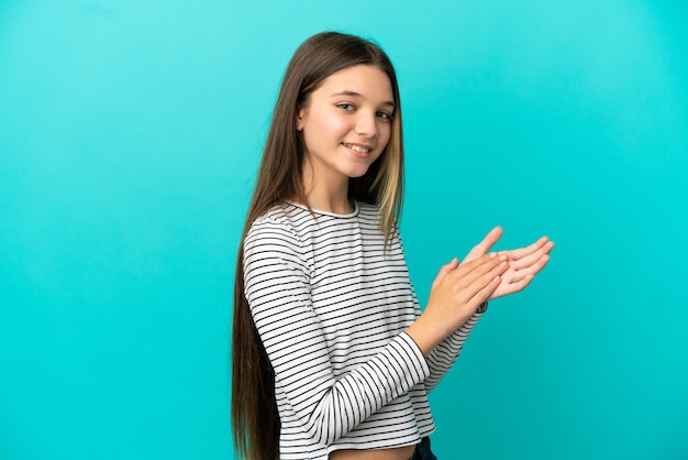 Petite fille sur fond bleu isolé applaudissant