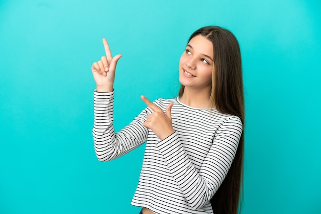 Petite fille sur fond bleu isolé pointant avec l'index une excellente idée