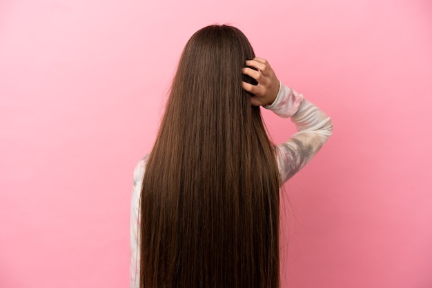 Petite fille sur fond rose isolé en position arrière et pensant