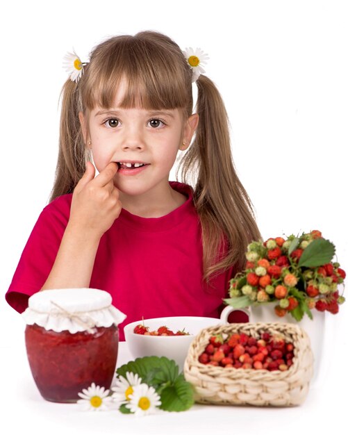 Petite fille avec des fraises de fleurs et de la confiture sucrée sur fond blanc