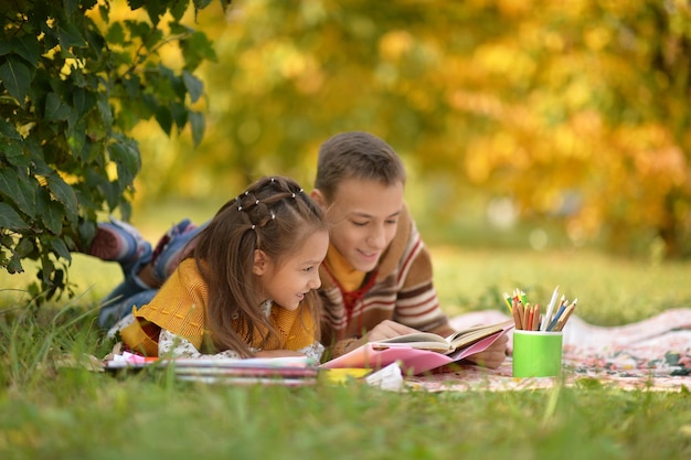 Petite fille et garçon lisant un livre à l'extérieur
