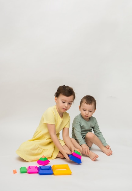 Petite fille et un garçon recueillent une pyramide multicolore sur fond blanc