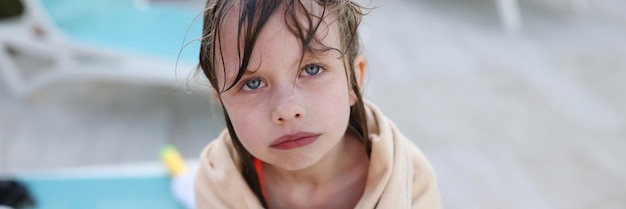 Petite fille gelée dans une serviette debout près de la piscine