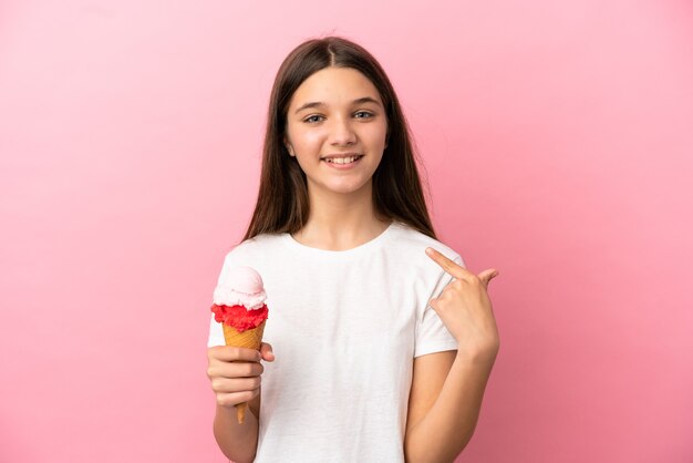 Petite fille avec une glace au cornet sur fond rose isolé donnant un geste du pouce vers le haut