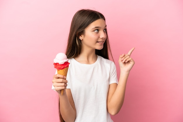 Petite Fille Avec Une Glace Au Cornet Sur Fond Rose Isolé Pointant Vers Une Excellente Idée