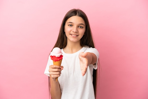 Petite fille avec une glace au cornet sur fond rose isolé se serrant la main pour conclure une bonne affaire