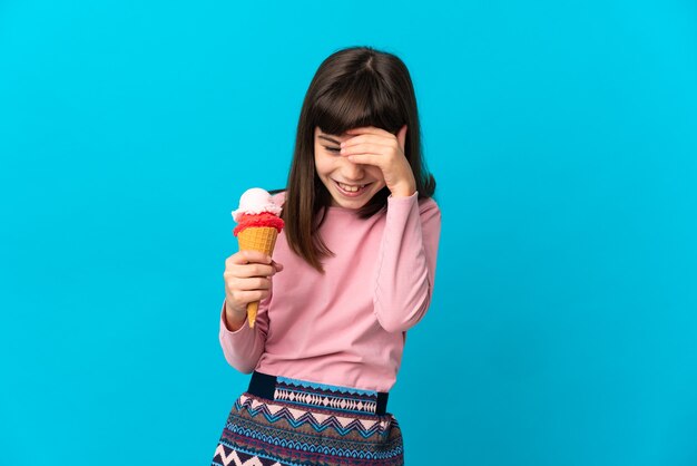 Petite fille avec une glace au cornet isolée sur fond bleu en riant