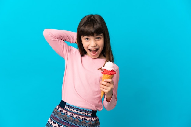 Petite fille avec une glace cornet isolée sur mur bleu en riant