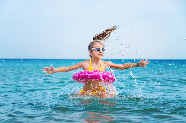 Petite fille avec gonflable rond rose dans la mer