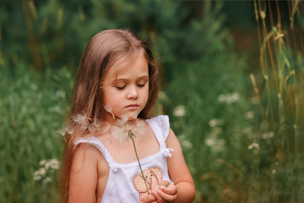 petite fille avec un gros pissenlit dans la nature en été