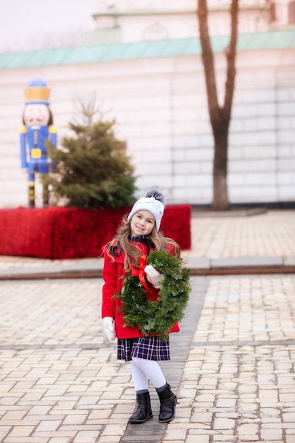 Petite fille avec guirlande de Noël dans la rue