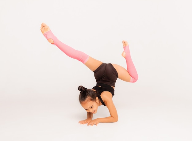 Petite fille gymnaste sur fond blanc. exercices sportifs. élongation. la flexibilité. aérobie