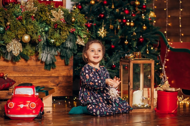 Petite fille habille un arbre de Noël à la maison