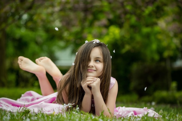 Petite fille sur l'herbe verte avec des pétales