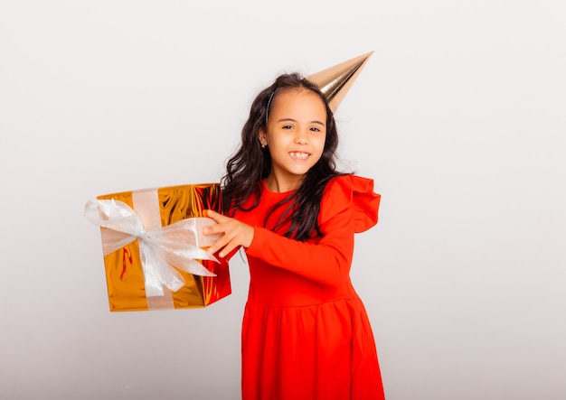 Une petite fille heureuse dans une casquette d'anniversaire tient une grande boîte-cadeau rouge. concept de vacances, place pour le texte