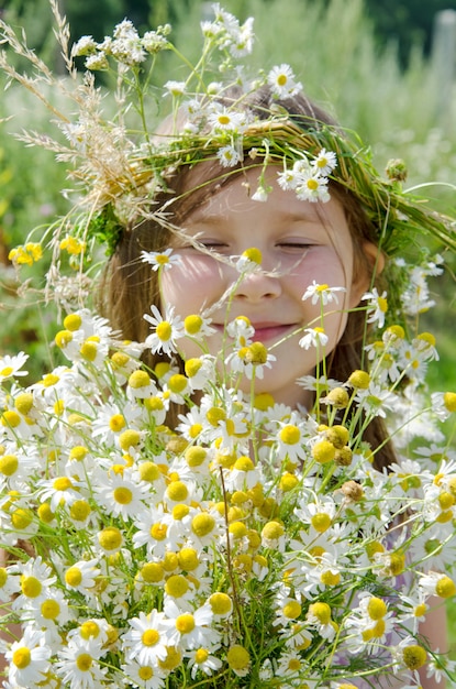 Petite fille heureuse dans une guirlande de fleurs des champs dans le pré