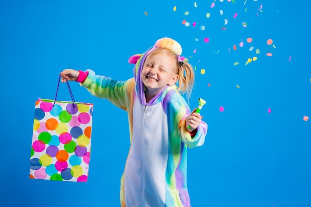 Une petite fille heureuse dans une licorne kigurumi tient un sac cadeau