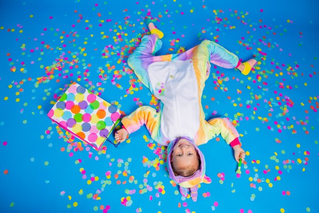 Une petite fille heureuse dans une licorne kigurumi tient un sac cadeau