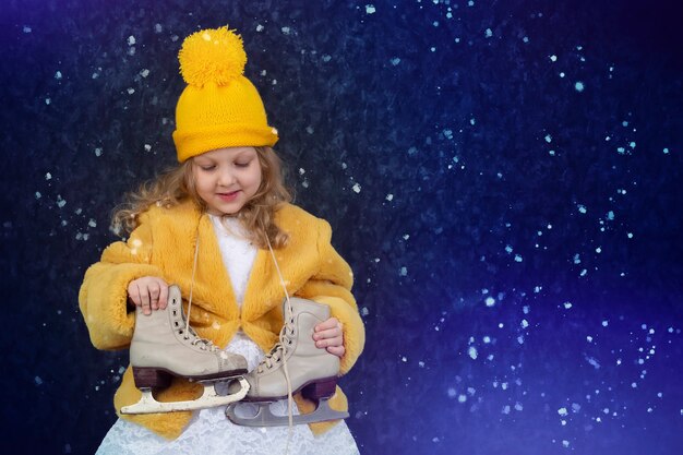 Petite fille heureuse dans un manteau de fourrure jaune et un bonnet tricoté