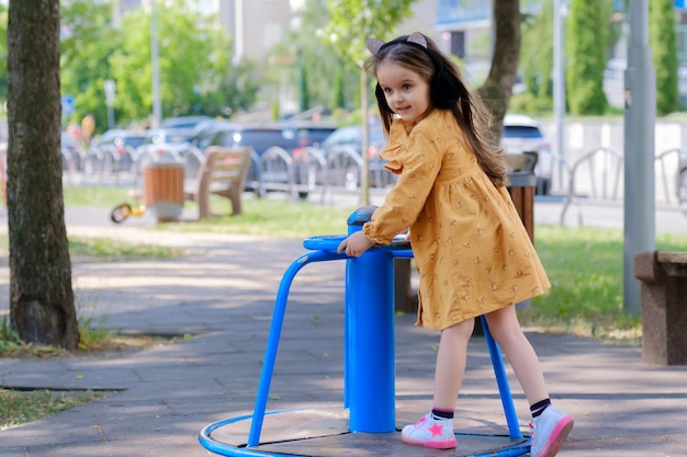 La petite fille heureuse joue sur le terrain de jeu en parc