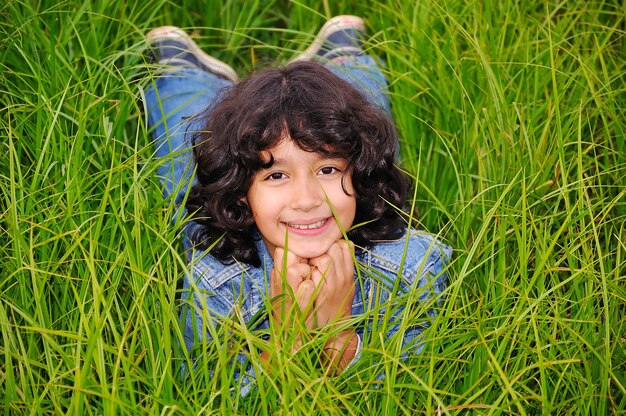 Une petite fille heureuse mignonne, couché sur un sol vert