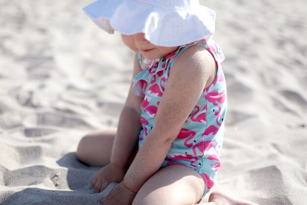 Petite fille heureuse sur la plage de sable blanc profitant de l'été et des vacances.