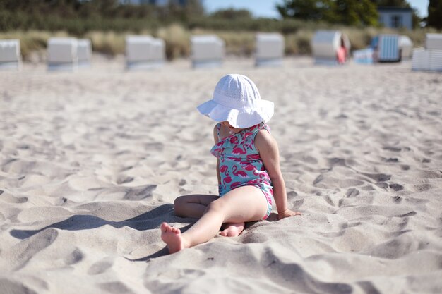 Petite fille heureuse sur la plage de sable blanc profitant de l'été et des vacances.