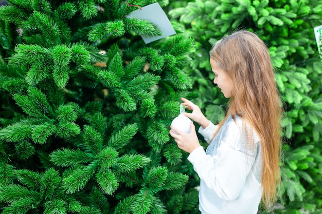 Petite fille heureuse près d'une branche de sapin dans la neige pour le nouvel an.