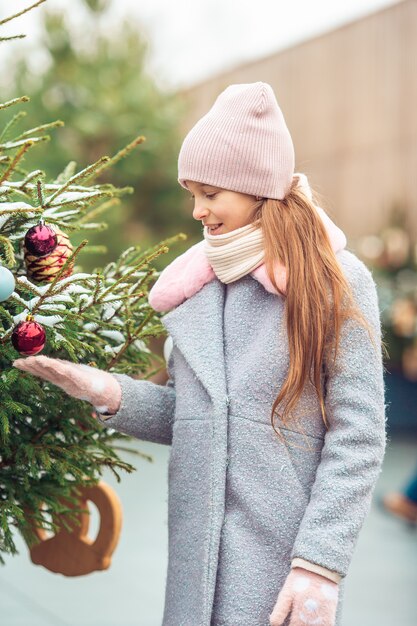 Petite fille heureuse près de branche de sapin dans la neige pour le nouvel an.