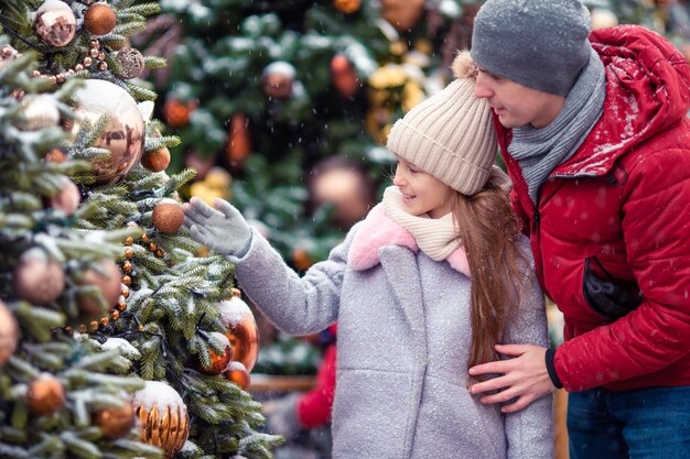 Petite fille heureuse près d'une branche de sapin dans la neige pour le nouvel an.