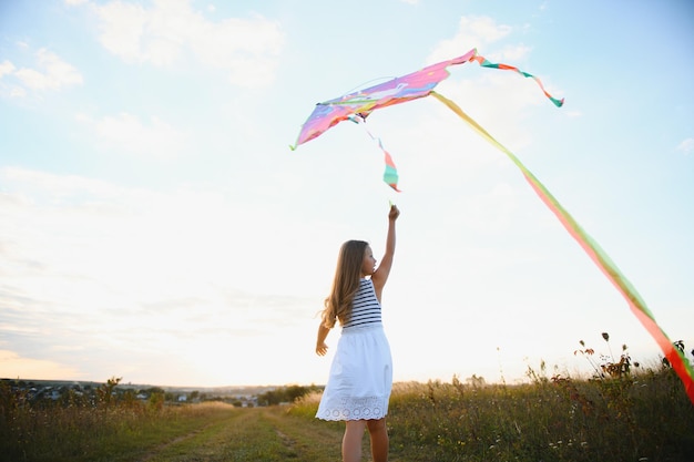 Une petite fille heureuse qui court sur le terrain avec un cerf-volant