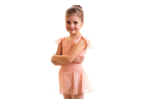 Petite fille heureuse en robe rose avec bundle dansant sur fond blanc en studio