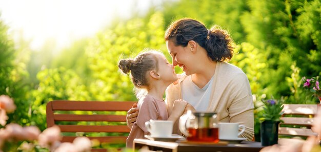 Une petite fille heureuse et sa mère buvant du thé un matin d'été La famille est assise dans le jardin