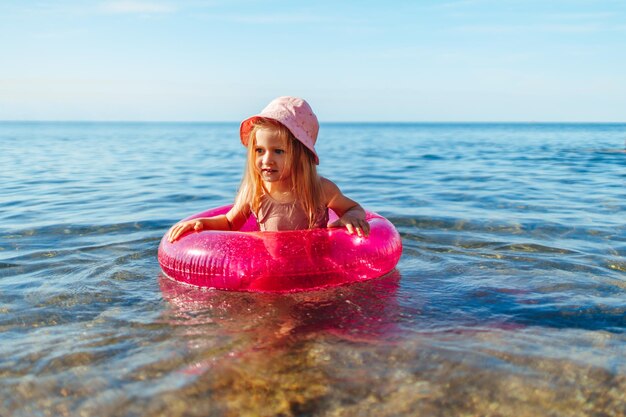 Petite fille heureuse se baignant en mer avec le cercle rose