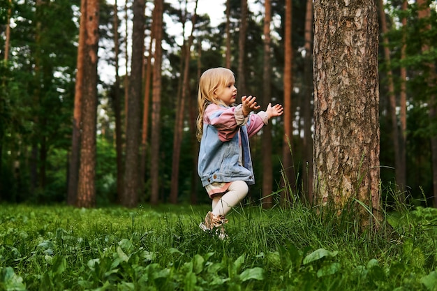 Une petite fille heureuse se familiarise avec la nature dans une forêt de pins
