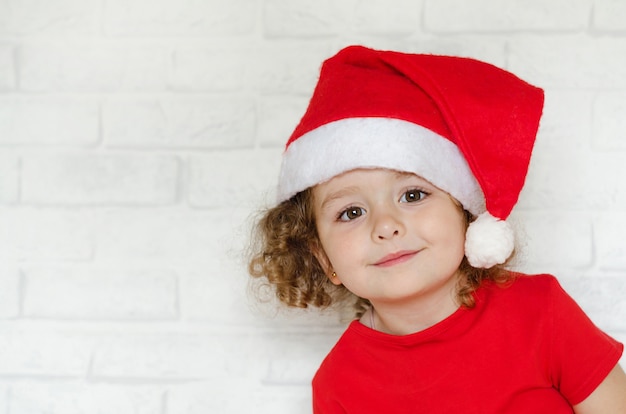 Petite fille heureuse souriante en bonnet de Noel pour joyeux Noël